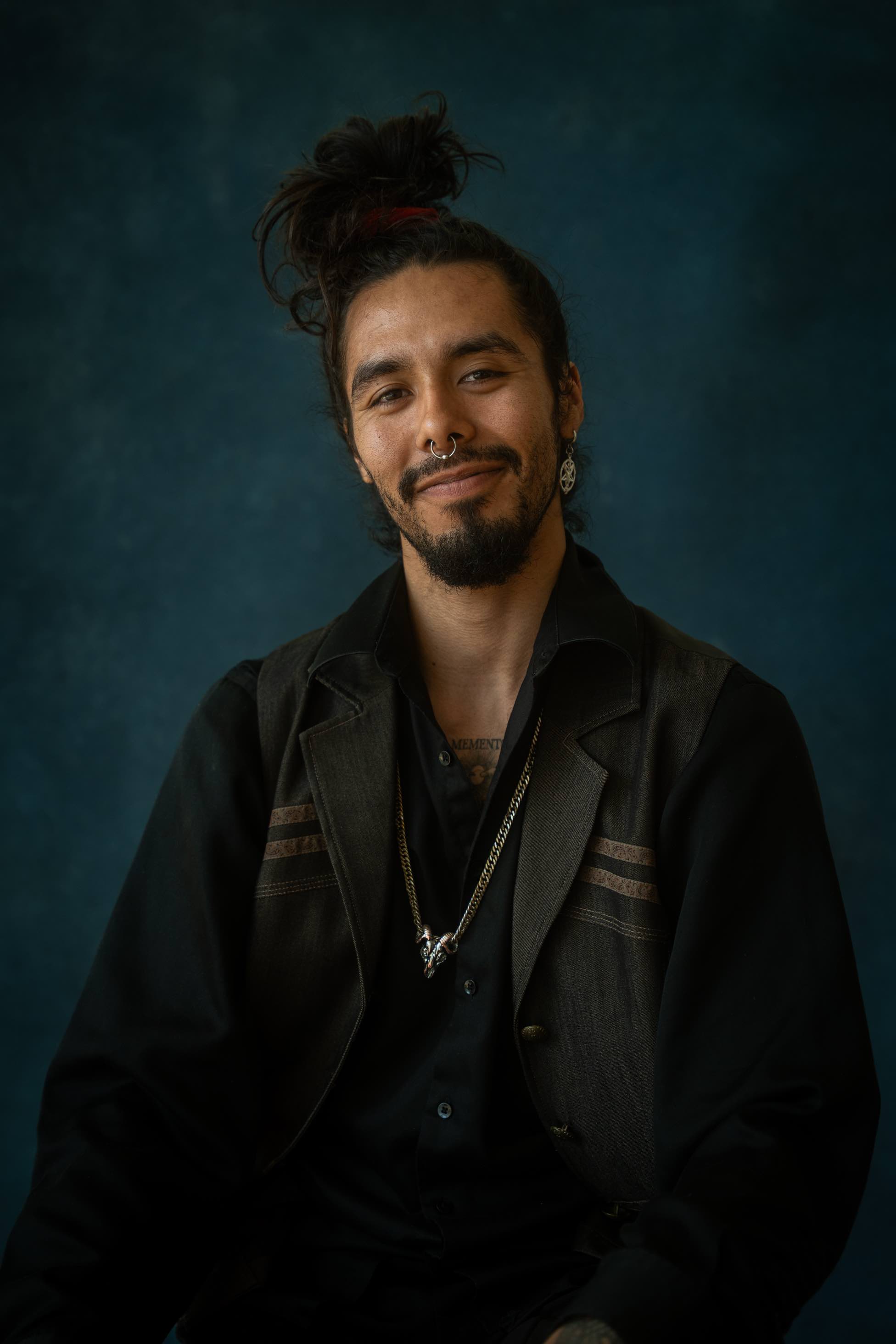 Portrait of Nicolás against a deep teal backdrop