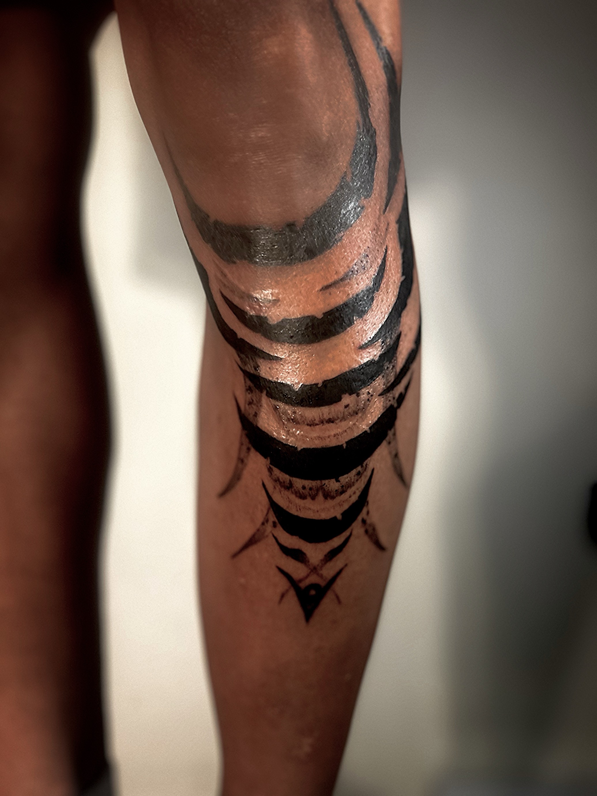 Abstract brushstroke tattoo on the leg