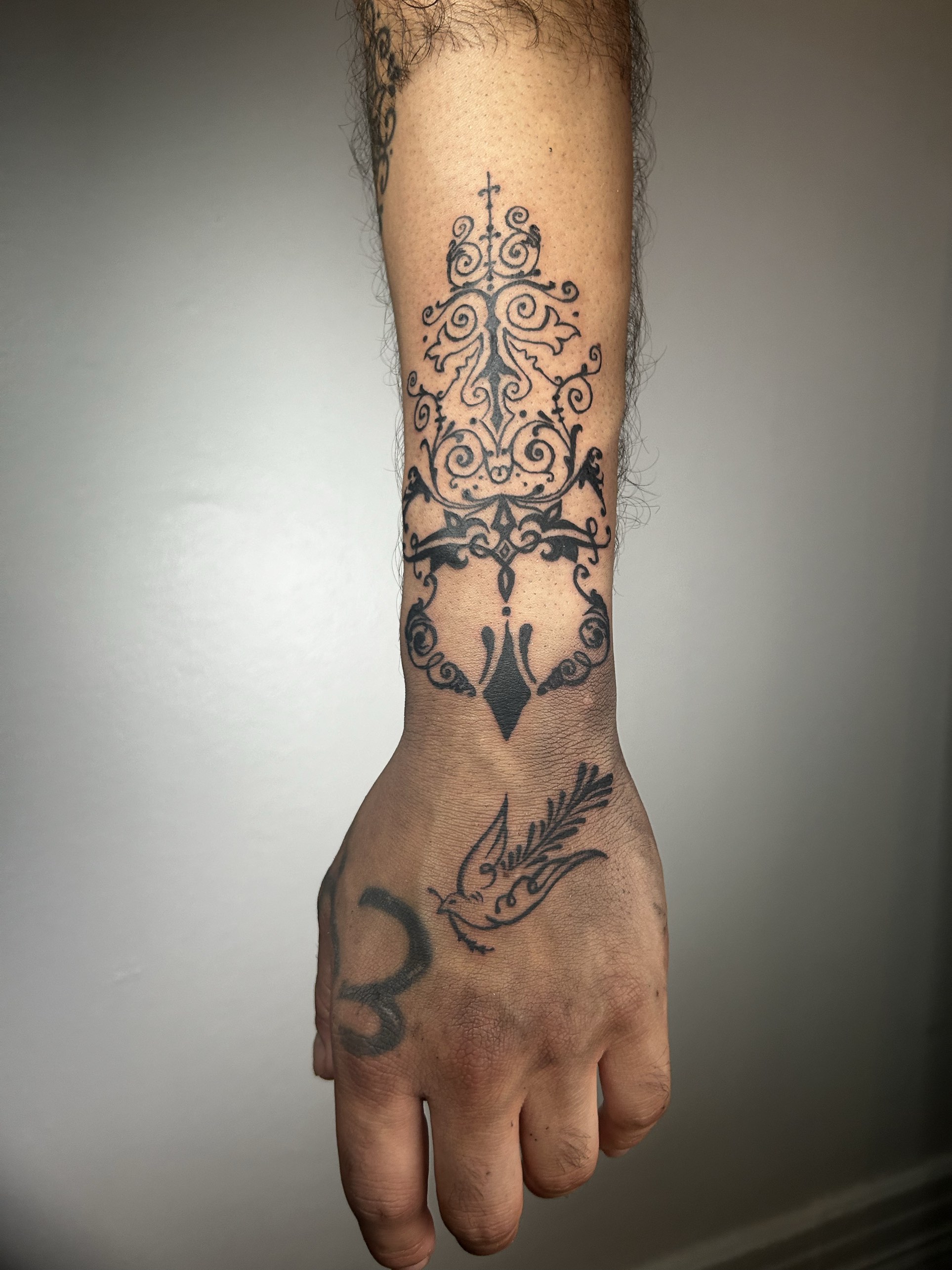 Ornamental filigree on the forearm with a dove on the hand